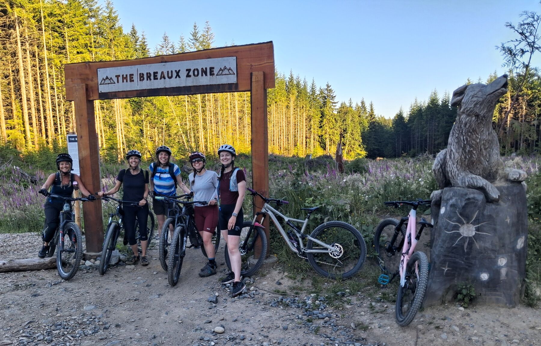 JoyRiders with their bikes under the Breaux Zone trail sign