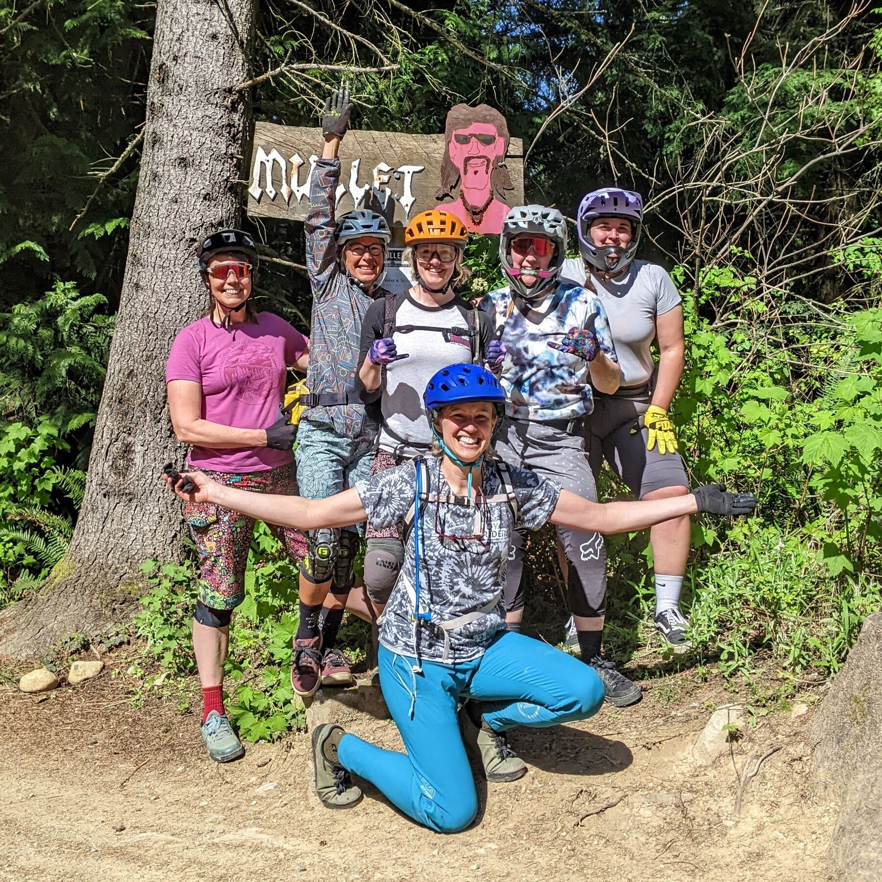 Six JoyRiders cheering under the Mullet trail sign on Galbraith